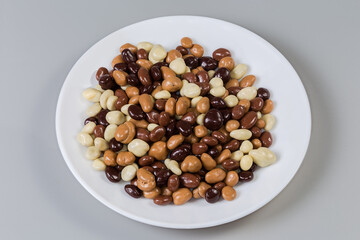Raisins covered with dark, white and milk chocolate on dish