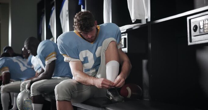 Team, locker room and football player preparing for game or practice at stadium field. Fitness, athlete and man tie laces in cloakroom getting ready for training or match of American contact sport.