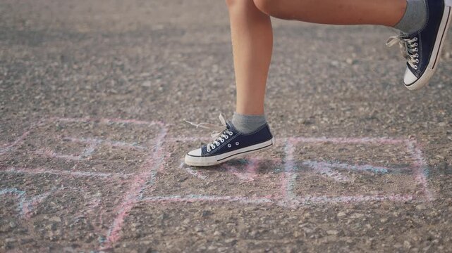 Child is playing game of hopscotch while jumping. happy family kid dream concept. a girl plays hopscotch on asphalt. a girl plays a game of hopscotch while a child jumps on the asphalt lifestyle.