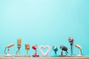 Retro microphones and concrete heart on table front gradient mint blue background. Vintage old style filtered photo