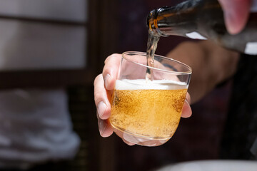 冷えたビールとグラスを持つ手 © Peak River