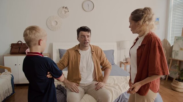 Medium long shot of Caucasian man mediating between his wife and son during family quarrel at home