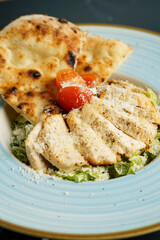 Caesar salad with fried chicken slices, tomato, parmesan cheese, tomato and crispy focaccia