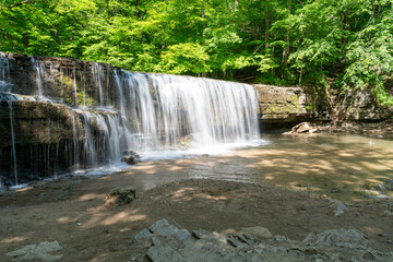 Fototapeta premium A beautiful view of a waterfall hidden away in a lush and green forest.