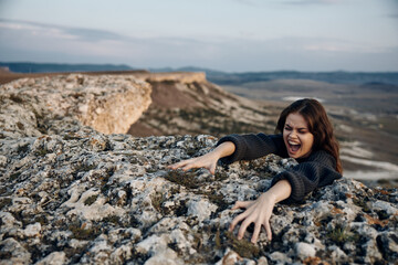 Brave woman scaling steep mountain cliff with arms outstretched in determination