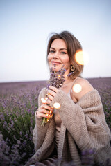 A smiling young woman smelling the scent of lavender in a lavender field.