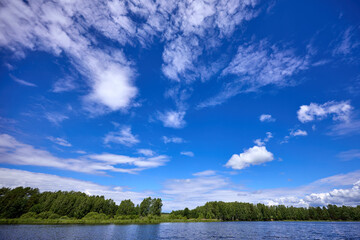 Beautiful summer river at sunny day with clouds reflection in the water