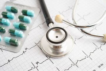 Stethoscope on electrocardiogram ECG with capsule drug, heart wave, heart attack, cardiogram report.