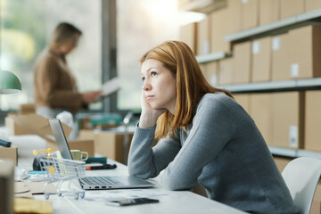 Pensive tired woman sitting at the desk and thinking