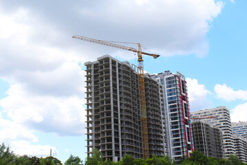 Fototapeta premium construction site with crane, new modern building under construction against blue sky 