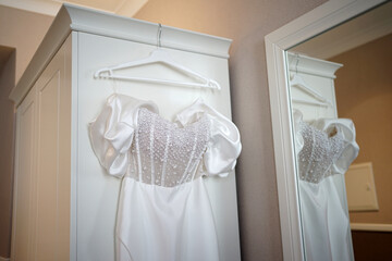 White wedding dress with stones in the room on a hanger.