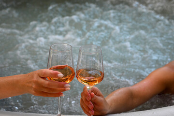 Two women are enjoying a relaxing soak in a hot tub, toasting with glasses of rose wine