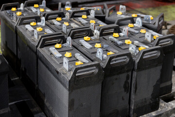 A stack of black locomotive batteries with yellow caps