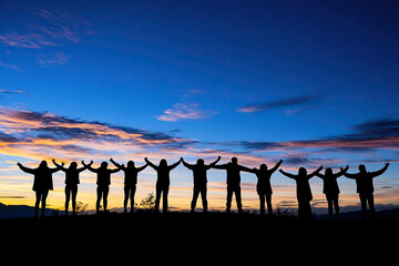 Fototapeta premium Silhouettes of group people men and women standing in celebration their victory at sunset