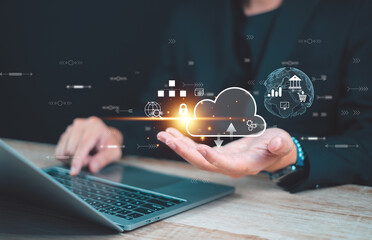 Businessman using a laptop for cloud computing technology and cloud storage while holding virtual hologram for online data management.