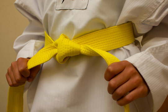 Kid in martial arts taekwondo or karate dobok uniform and holding yellow belt