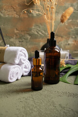 Spa Essentials and Amber Duo Bottles on Surface with Towels and Leaf