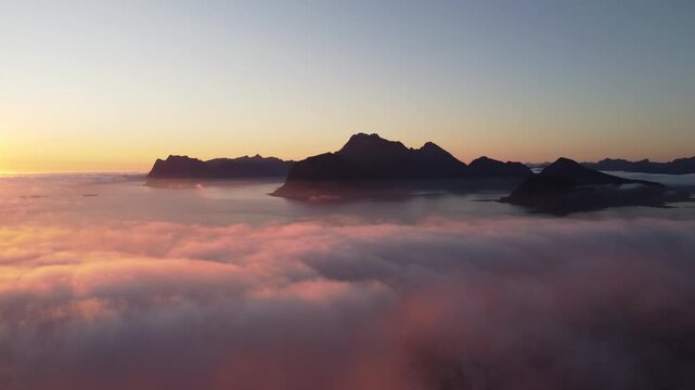 Dreamy aerial view over clouds with midnight sun in Lofoten, Northern Norway