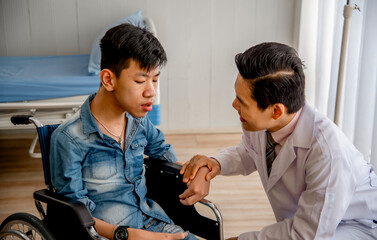 Doctor comforting a young patient in a wheelchair, offering care and support in a medical setting....