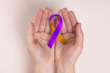 World Psoriasis Day. Woman with orange and orchid ribbon as symbol of support on beige background, top view