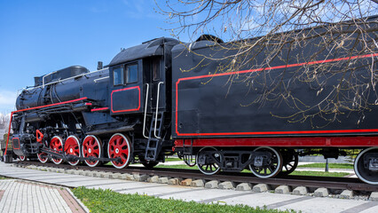 An old black steam locomotive.  
A large mainline passenger steam locomotive. Ancient railway transport. Transportation of goods by rail. A coal-fired steam locomotive.