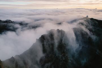 Aerial view of majestic mountain ridges at sunrise with falling fog from top of Pico do Areeiro, Madeira island, Portugal