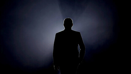 Silhouette of a man in classic suit against a backlight. A sophisticated and elegant image ideal for highlighting professionalism, formal events, and stylish fashion.