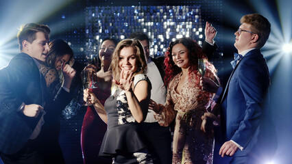 Young people dancing to electronic music, jumping and having fun on the dance floor under vibrant...