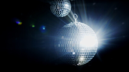 Close-up of a spinning disco ball reflecting dynamic rays of light against a black background....