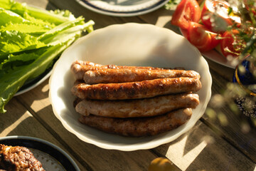 BBQ food. Plate of grilled sausages on wooden table.