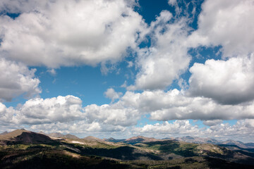 The shadows from the billowing clouds overhead dance across the Rocky Mountains in Rocky Mountain National Park, Colorado in mid-August