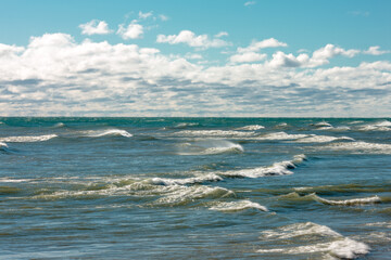 Looking out over Lake Michigan as the waves rush to the shoreline under the partially cloudy sky at Harrington Beach State Park, Belgium, Wisconsin in early October