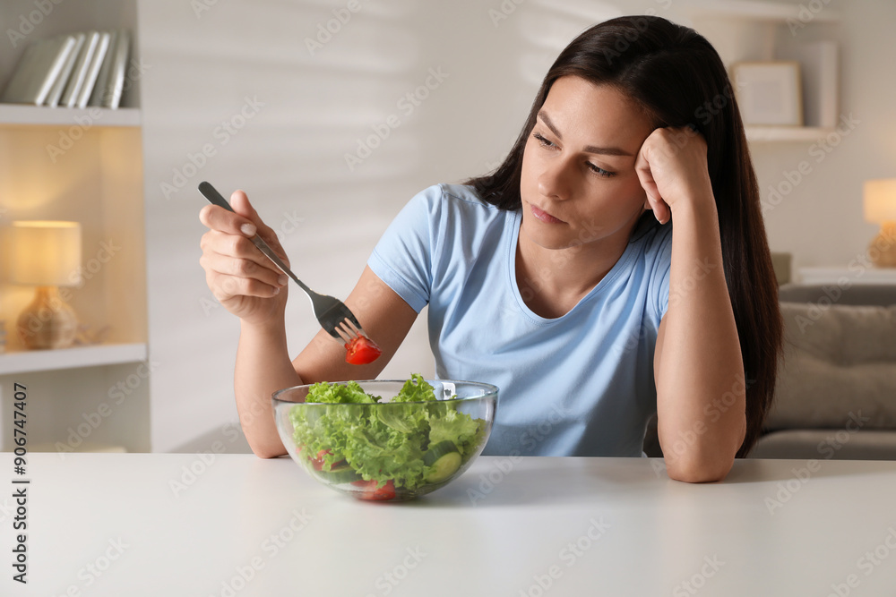 Poster Eating disorder. Sad woman holding fork with tomato over bowl at table indoors