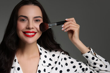 Obraz premium Beautiful makeup. Smiling woman with brush on grey background