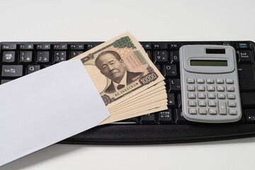 日本円の一万円札で新紙幣の封筒入りの10万円とキーボード