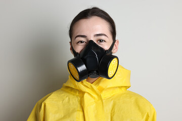 Worker in respirator and protective suit on grey background