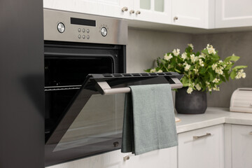 Open electric oven with towel in kitchen. Cooking appliance