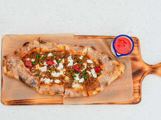 Pie open pide with beef and feta cheese and red sauce, top view