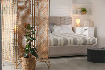 Folding screen and comfortable bed in bedroom. Interior design