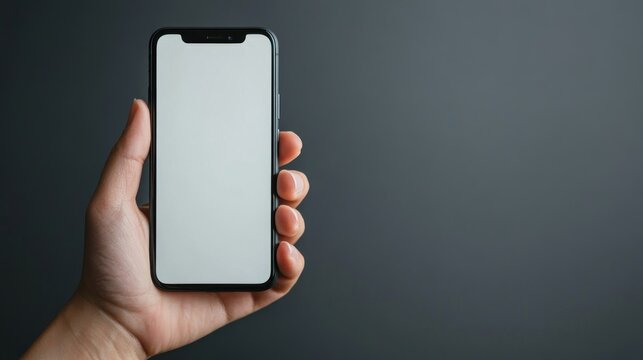 A left-handed person holding a smartphone with their left hand, using the screen. The phone and hand are in focus with a minimalistic background to ensure plenty of copy space.