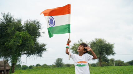 Boy saluting and holding Indian flag in Patriotic mood on the Occasion of Independence Day India celebrations