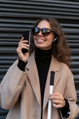 Young deafblind woman with white cane and hearing aids talking on a call with her mobile phone