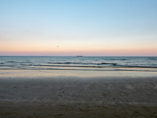 Airplane flying low above calm smooth blue Mediterranean sea with long cargo ship navigating at the horizon. Preparing to land at the airport of Larnaca, Cyprus.
