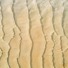 Fototapeta premium Sunlight reflecting on lines of water flowing over beach sand