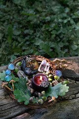 candle, moon amulet, minerals, acorns, oak leaves, mushrooms in forest, natural background. forest...