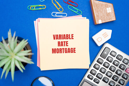 Variable rate mortgage concept. Type of home loan in which the interest rate is not fixed. Real estate, business and finance concept. Miniature houses, magnifying glass, calculator and notes