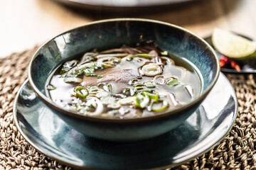 Pho Bo Vietnamese fresh rice noodle soup with beef, onions, lime, herbs and chilli decoration