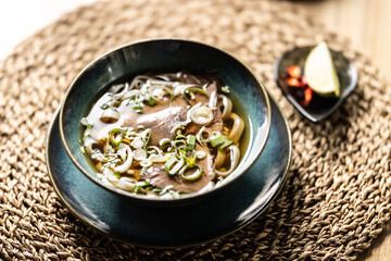 Pho Bo Vietnamese fresh rice noodle soup with beef, onions, lime, herbs and chilli decoration