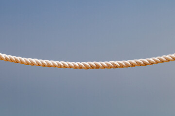 curved sea rope hanging on blue sky background