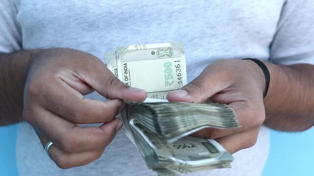 Man counting 500 Indian rupee banknotes